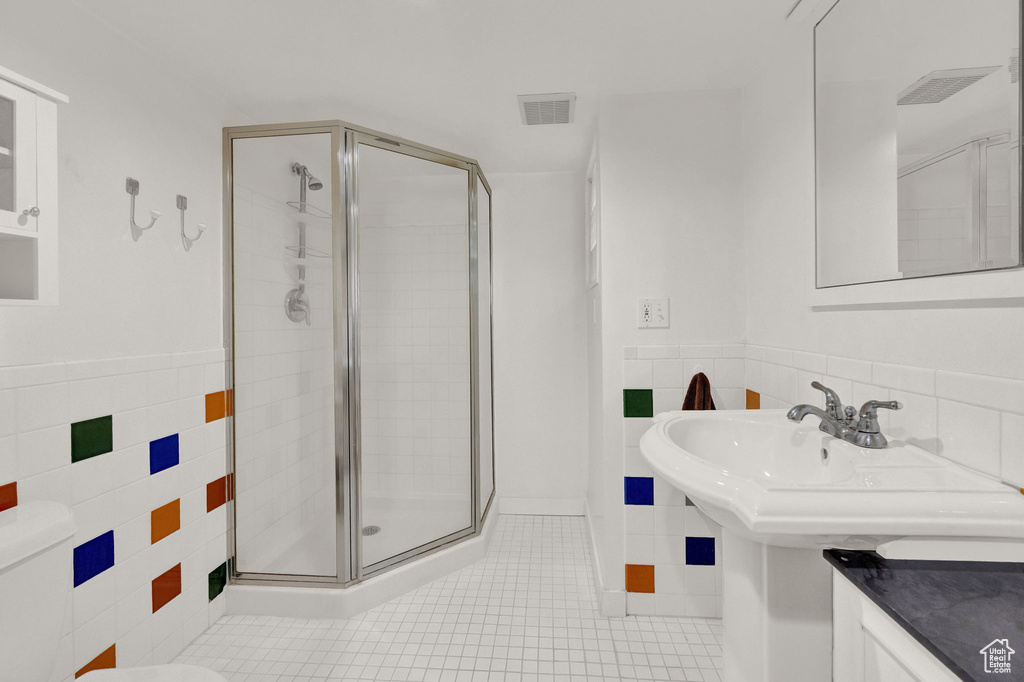 Bathroom with tile walls, toilet, tile floors, and a shower with shower door