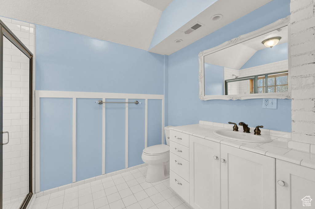 Bathroom featuring tile flooring, an enclosed shower, toilet, vaulted ceiling, and vanity
