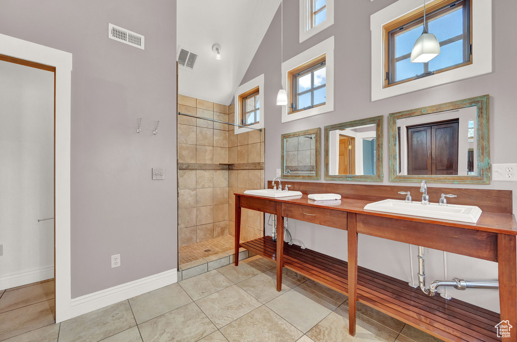 Bathroom featuring tile flooring, high vaulted ceiling, dual vanity, and tiled shower