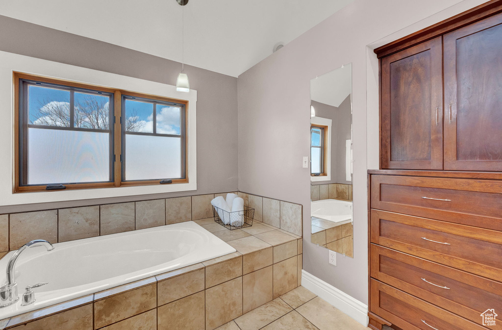 Bathroom featuring tile flooring, plenty of natural light, and tiled bath