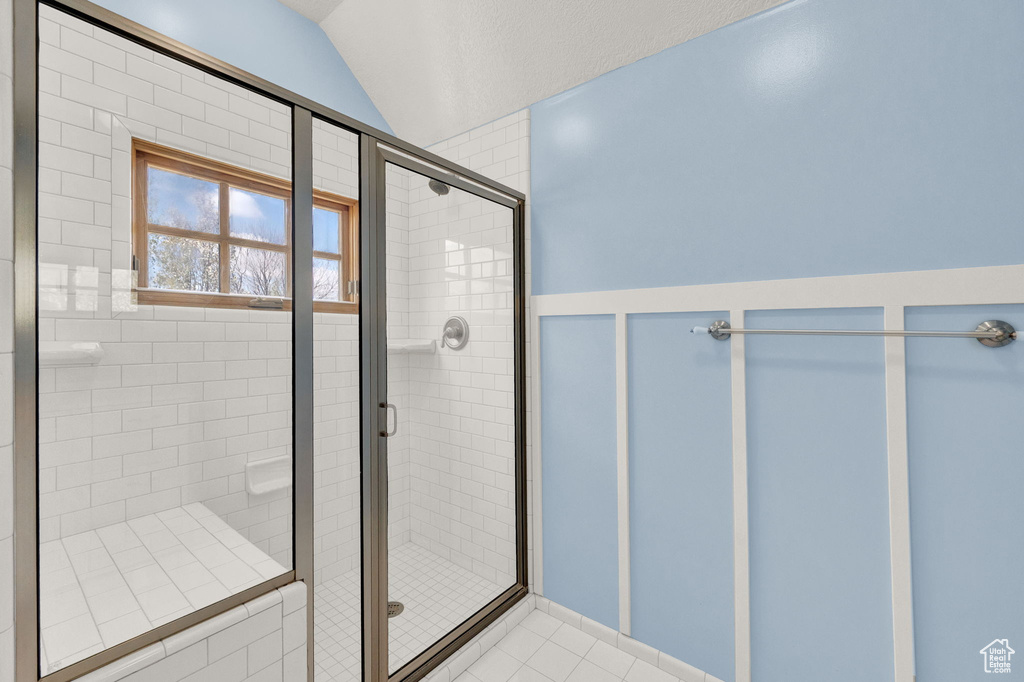 Bathroom with walk in shower, tile flooring, and lofted ceiling