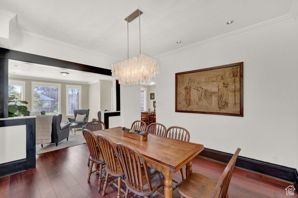 Dining space with dark hardwood / wood-style flooring, crown molding, and an inviting chandelier