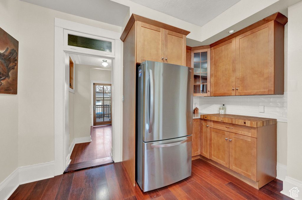 Kitchen with tasteful backsplash, dark hardwood / wood-style flooring, and stainless steel refrigerator