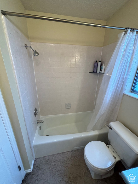 Bathroom featuring shower / bath combo, toilet, and a textured ceiling