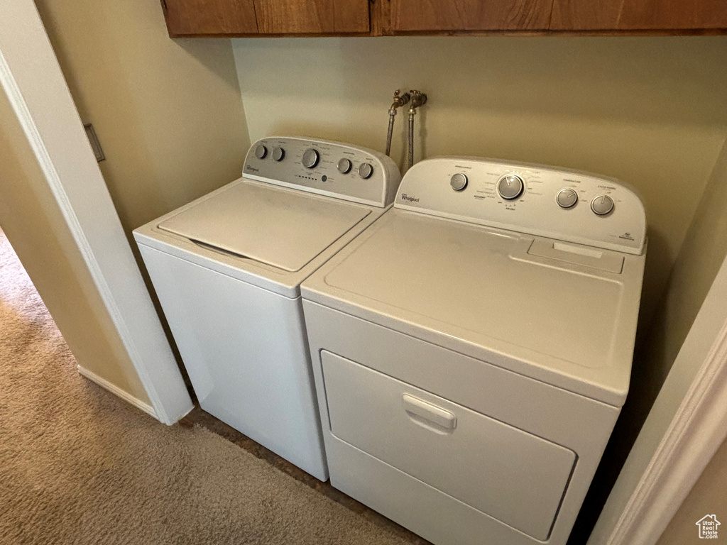Laundry room featuring cabinets, light carpet, and washing machine and clothes dryer