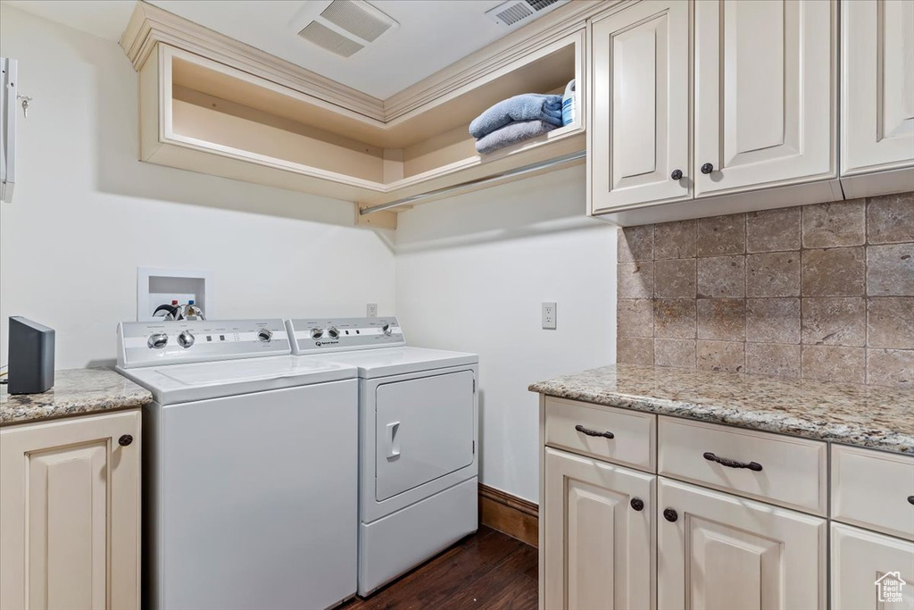 Washroom featuring washing machine and dryer, cabinets, and dark hardwood / wood-style floors