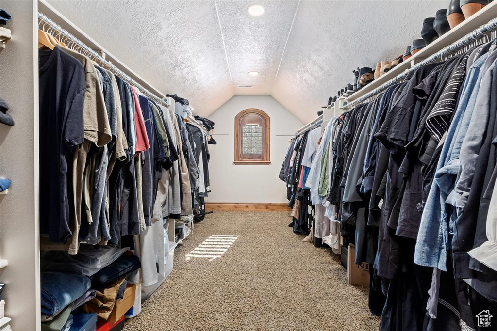Spacious closet with dark colored carpet and vaulted ceiling