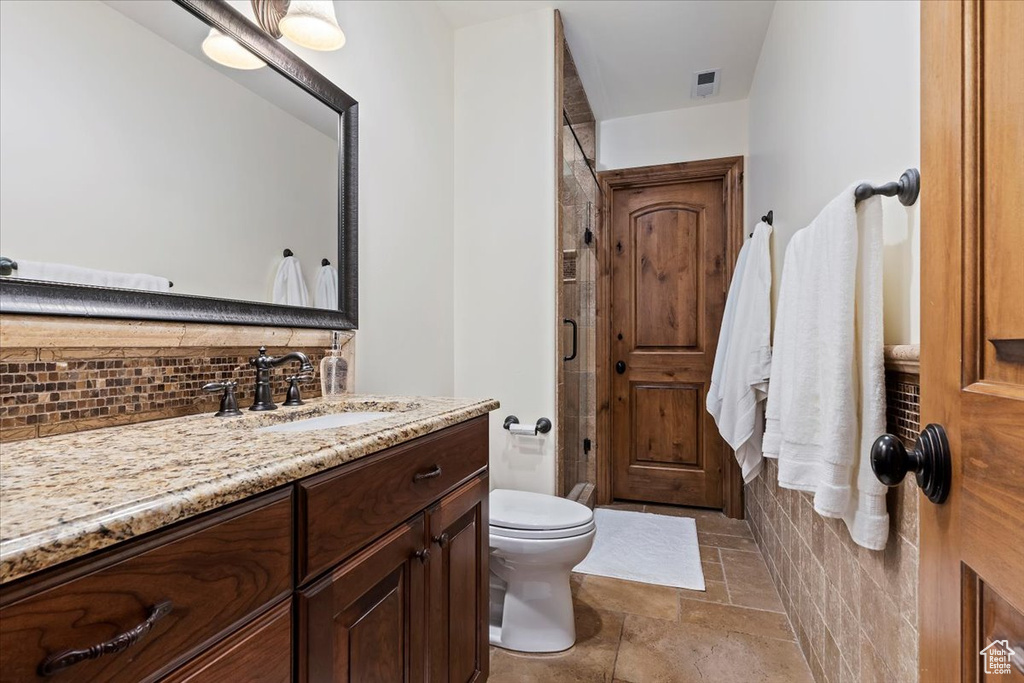 Bathroom with tile floors, vanity, backsplash, and toilet
