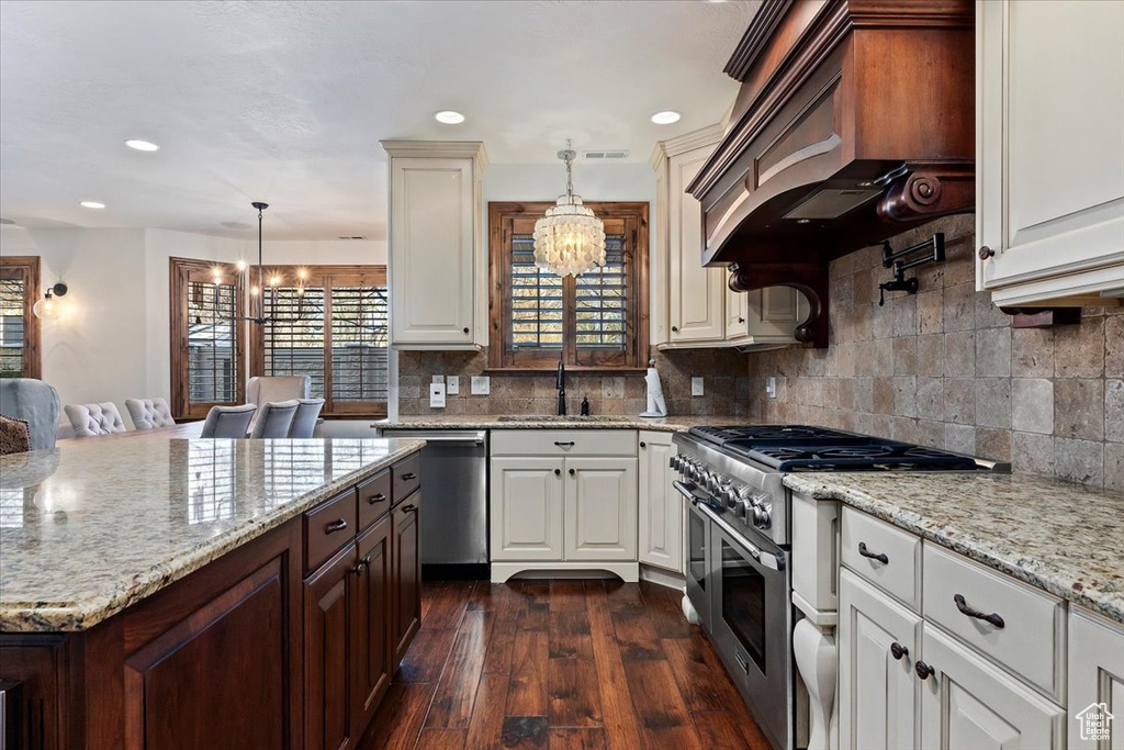Kitchen with appliances with stainless steel finishes, backsplash, pendant lighting, and dark hardwood / wood-style floors