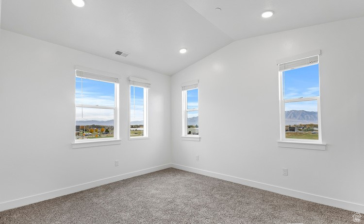 Carpeted empty room with a mountain view and vaulted ceiling