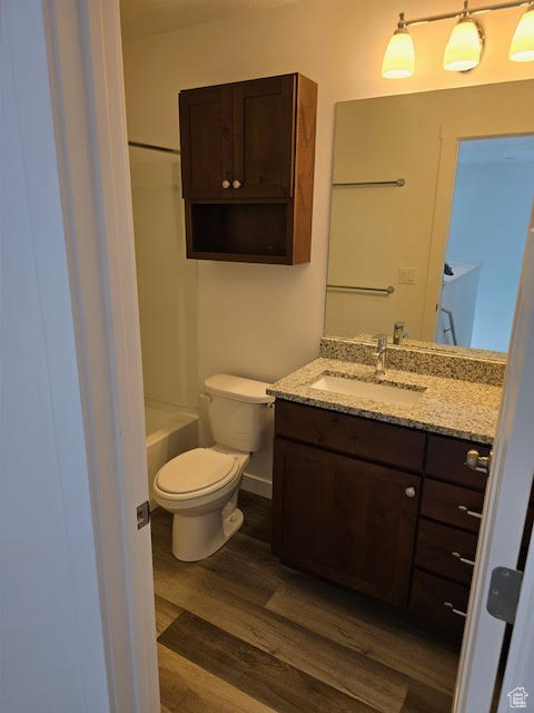 Full bathroom with bathtub / shower combination, toilet, hardwood / wood-style flooring, and vanity
