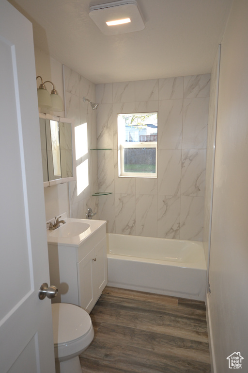 Full bathroom with wood-type flooring, tiled shower / bath combo, and vanity