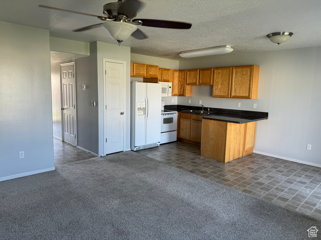 Kitchen featuring ceiling fan, white appliances, dark carpet, and sink