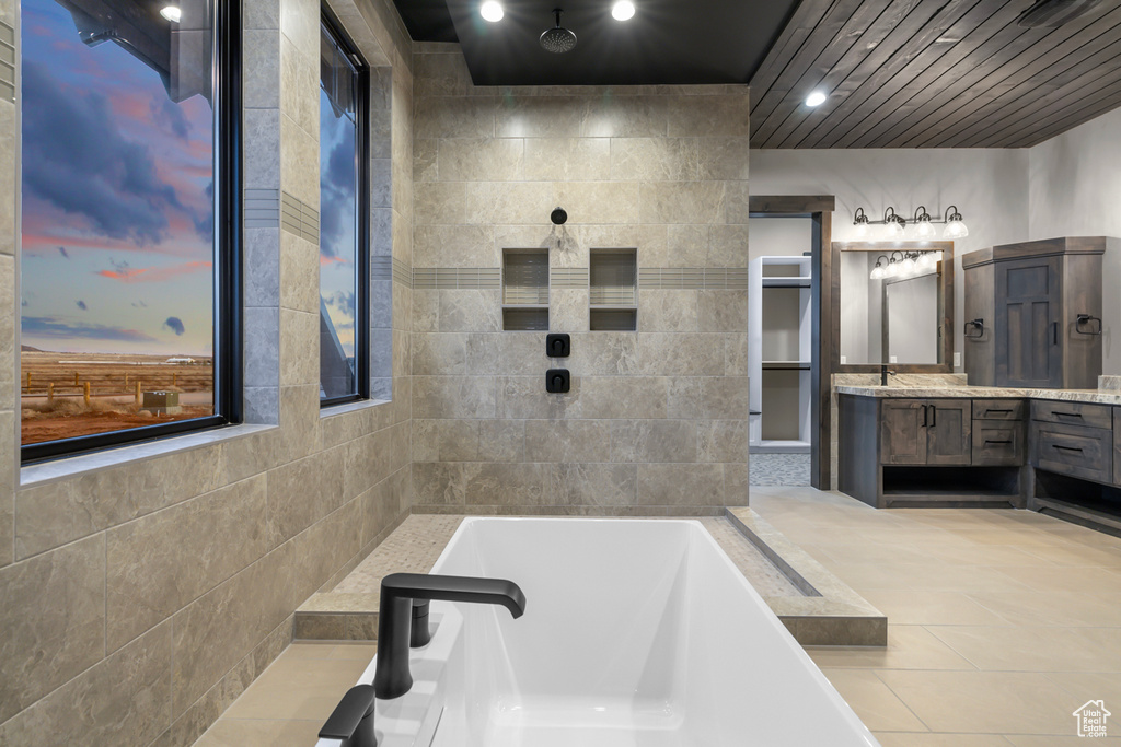 Bathroom featuring tile walls, separate shower and tub, tile floors, and vanity