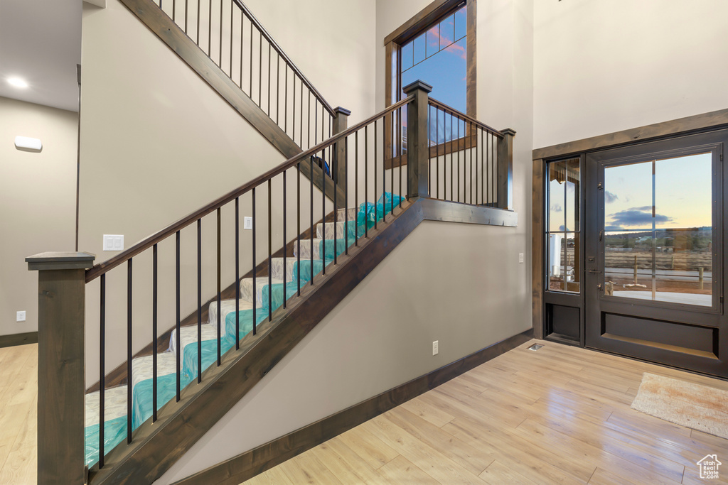 Stairs with light hardwood / wood-style floors and a high ceiling