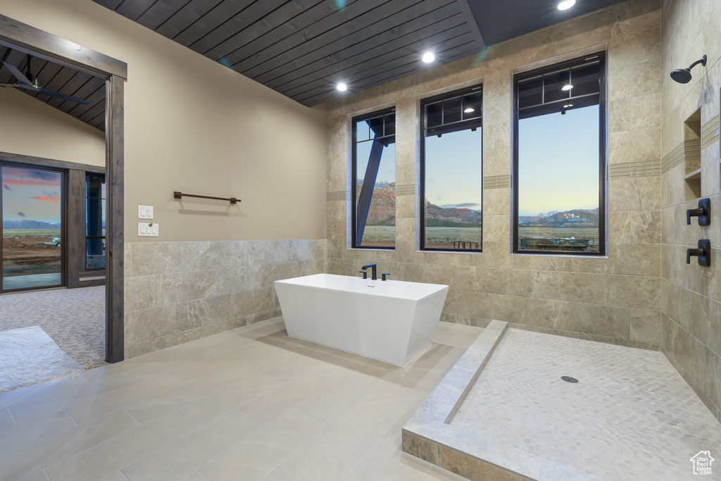 Bathroom featuring independent shower and bath, tile walls, tile floors, and a wealth of natural light