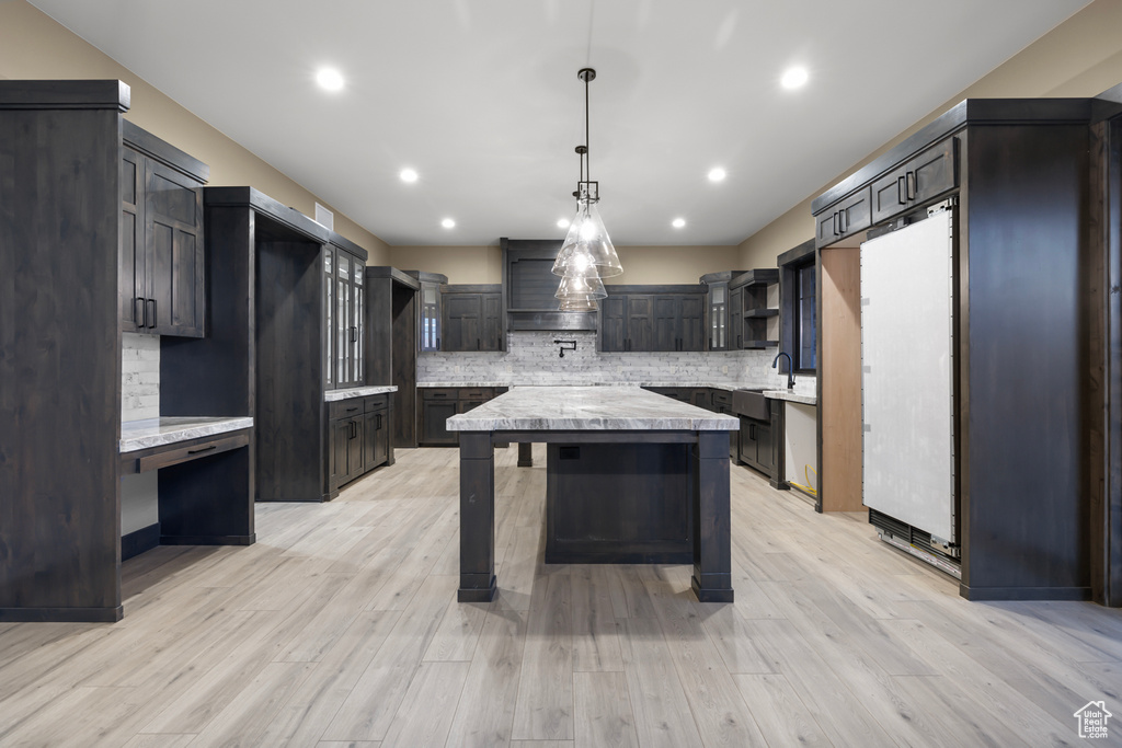 Kitchen with backsplash, a kitchen island, and light wood-type flooring