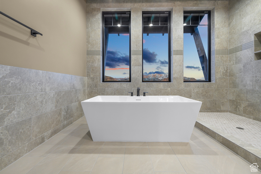 Bathroom featuring a bathing tub, tile floors, and tile walls