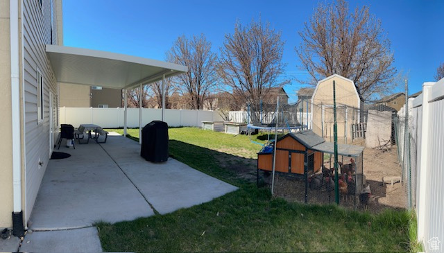 View of yard featuring a trampoline and a patio area