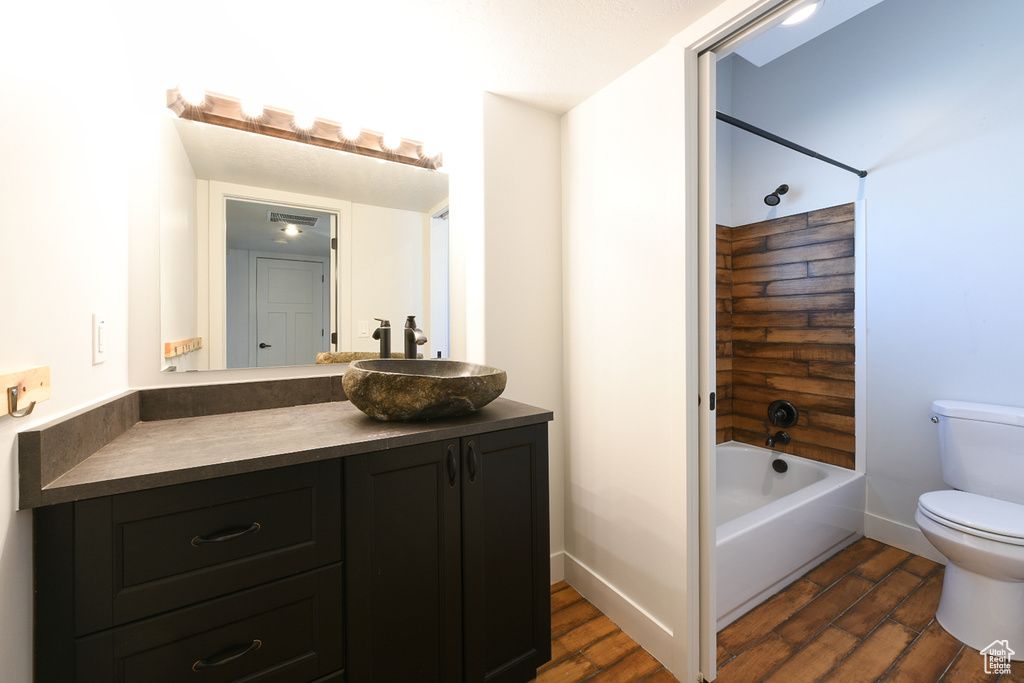 Full bathroom with hardwood / wood-style floors, shower / washtub combination, vanity, and toilet