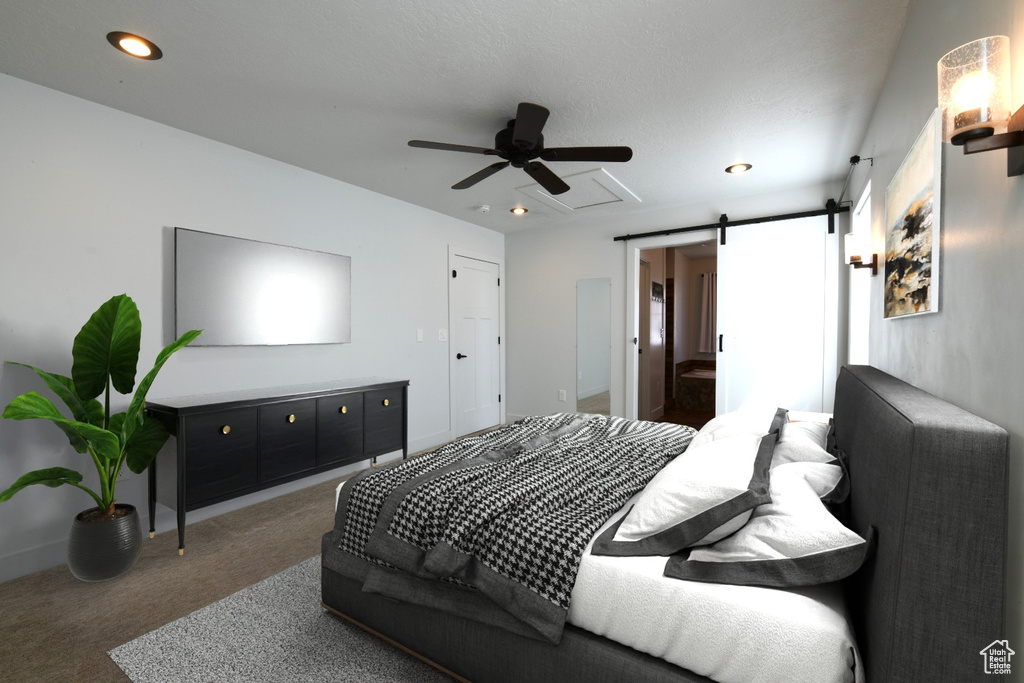 Bedroom with dark colored carpet, ceiling fan, and a barn door