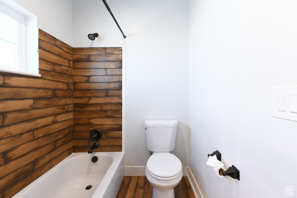 Bathroom featuring hardwood / wood-style floors, toilet, and bathing tub / shower combination