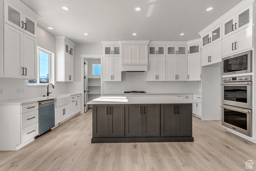 Kitchen with a kitchen island, stainless steel appliances, and white cabinetry