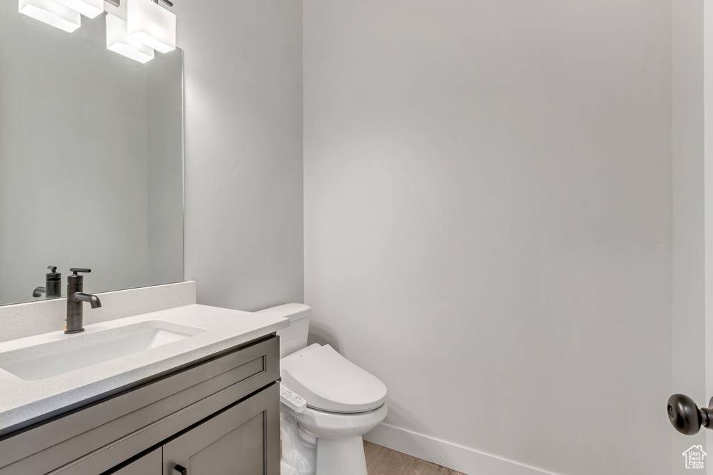 Bathroom featuring hardwood / wood-style floors, vanity with extensive cabinet space, and toilet