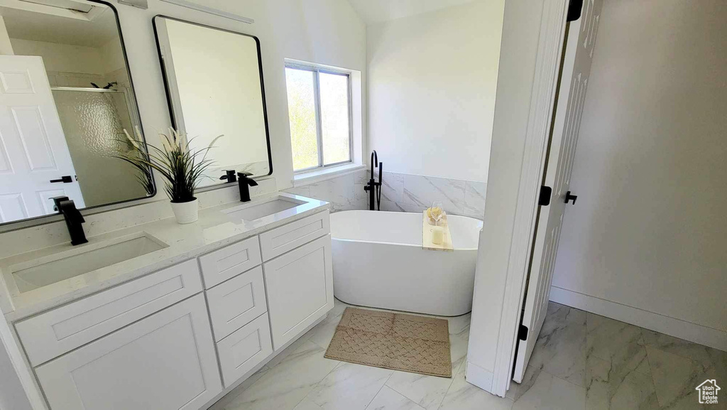 Bathroom featuring tile flooring, double sink vanity, and a tub