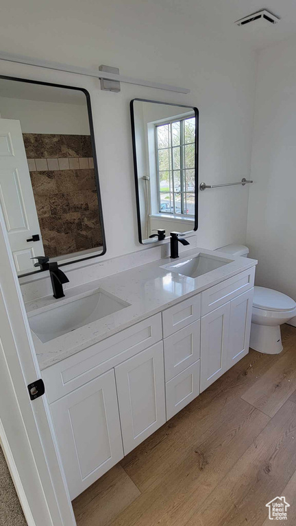 Bathroom with wood-type flooring, toilet, and double vanity