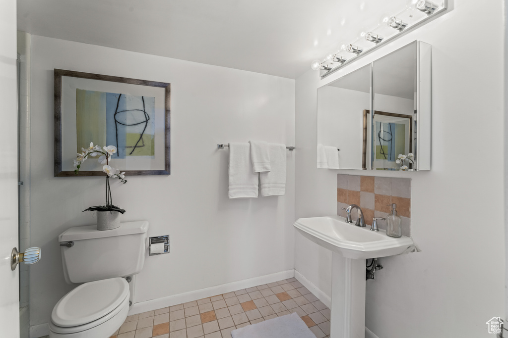 Bathroom with tasteful backsplash, tile floors, and toilet