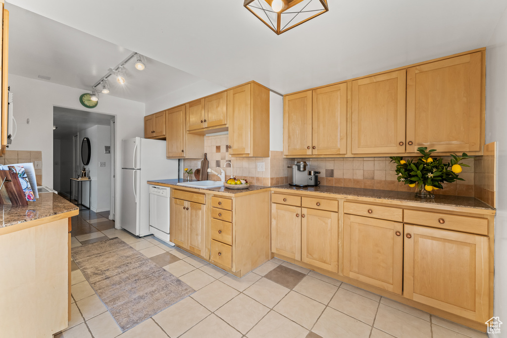Kitchen featuring backsplash, light brown cabinets, rail lighting, and light tile floors