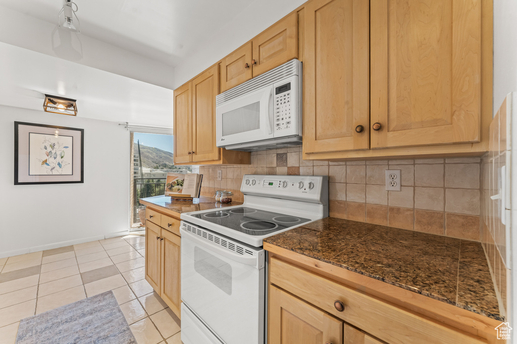Kitchen with light brown cabinets, white appliances, tasteful backsplash, and light tile floors