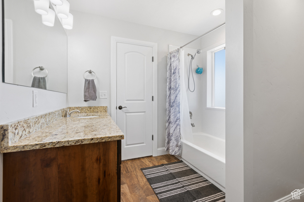 Bathroom featuring hardwood / wood-style floors, shower / bathtub combination with curtain, and vanity