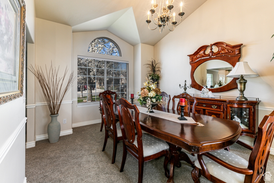 Dining area with an inviting chandelier, light carpet, and vaulted ceiling