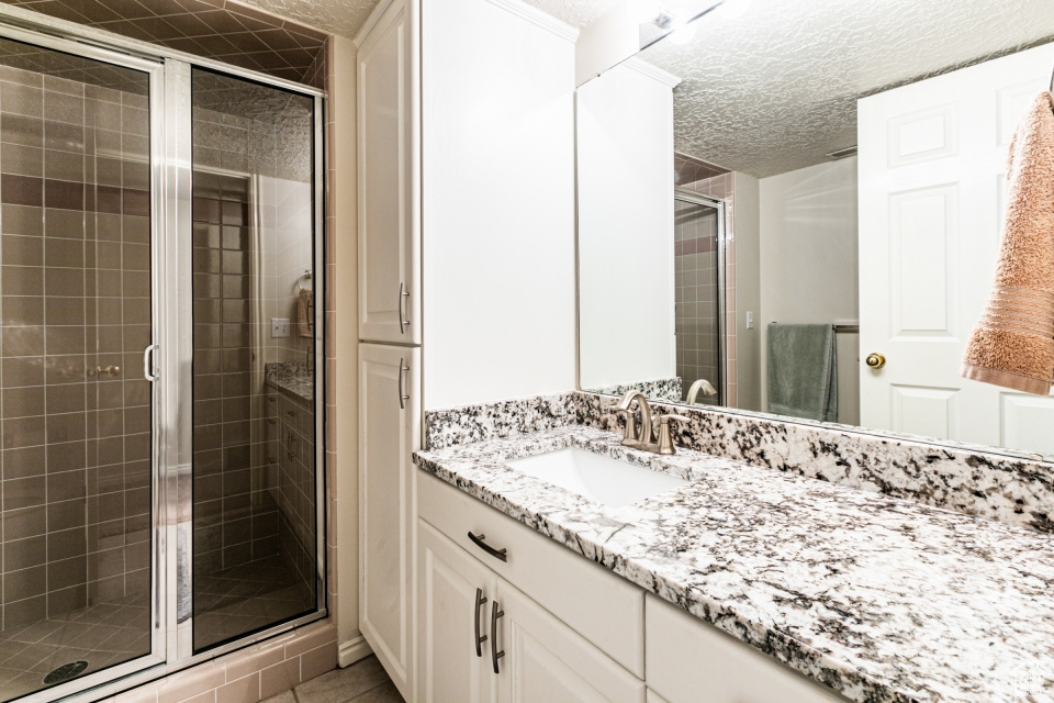 Bathroom featuring vanity, an enclosed shower, and a textured ceiling
