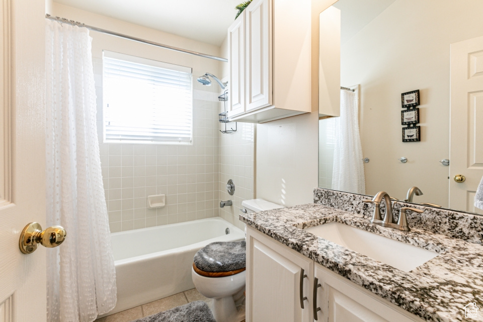 Full bathroom featuring vanity with extensive cabinet space, toilet, tile floors, and shower / tub combo with curtain