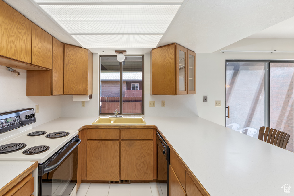 Kitchen with electric range, dishwasher, sink, and light tile flooring