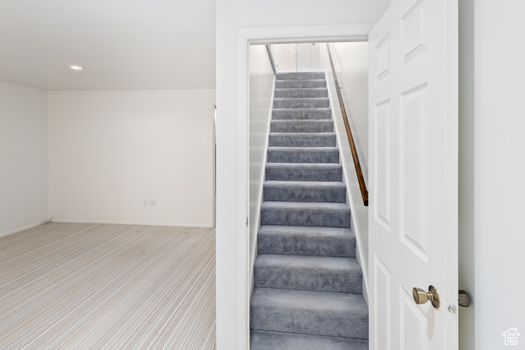 Staircase featuring light colored carpet
