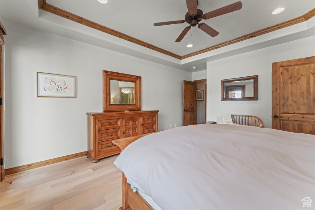 Bedroom featuring crown molding, ceiling fan, a tray ceiling, and light hardwood / wood-style flooring