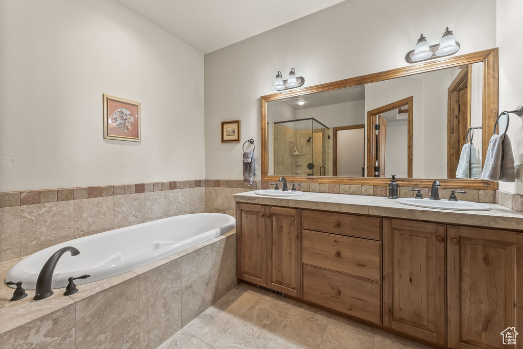 Bathroom featuring oversized vanity, plus walk in shower, dual sinks, and tile floors