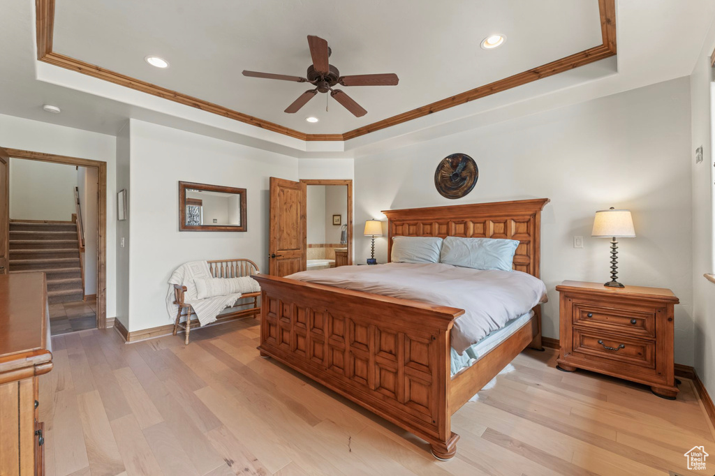 Bedroom with ornamental molding, ceiling fan, a raised ceiling, and light hardwood / wood-style flooring