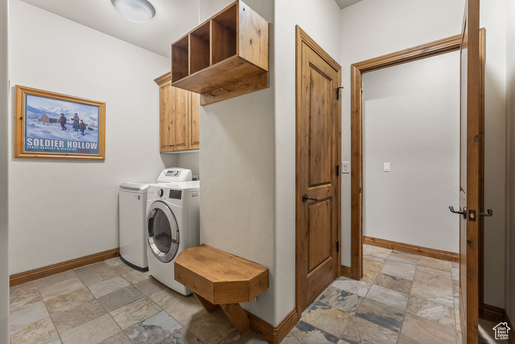 Laundry room featuring light tile floors, cabinets, and separate washer and dryer