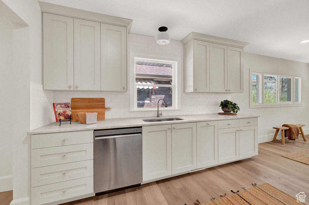 Kitchen featuring light hardwood / wood-style flooring, sink, tasteful backsplash, and dishwasher