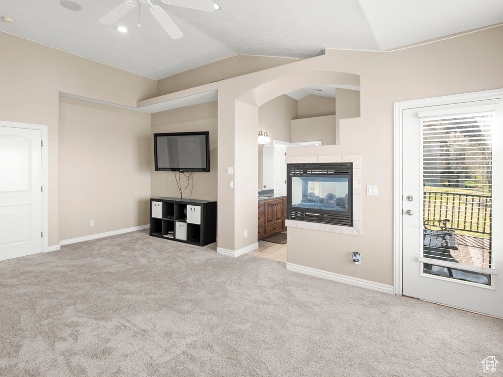 Unfurnished living room with vaulted ceiling, ceiling fan, light carpet, and a multi sided fireplace