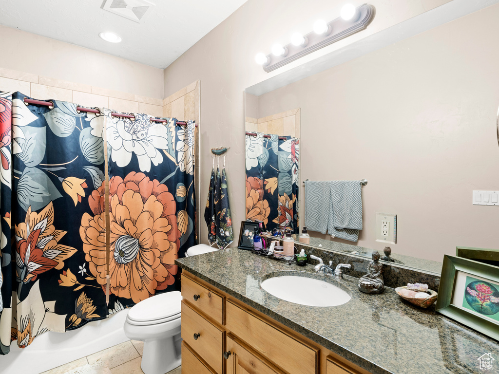 Full bathroom featuring large vanity, shower / bathtub combination with curtain, tile floors, and toilet