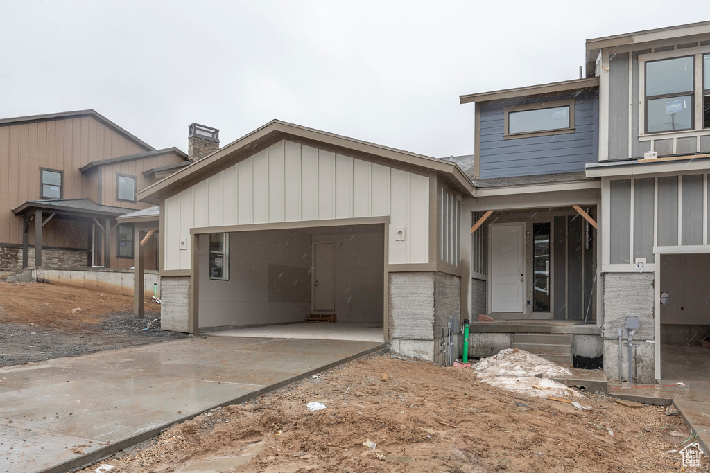 View of side of home featuring a garage, concrete driveway, and a chimney