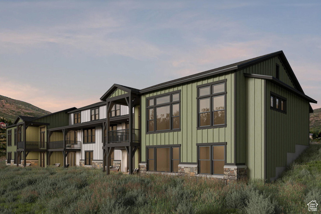 Back of house at dusk featuring board and batten siding and stone siding