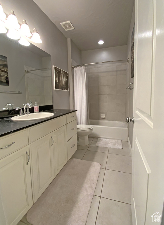Full bathroom with tile floors, vanity, toilet, and shower / bathtub combination with curtain