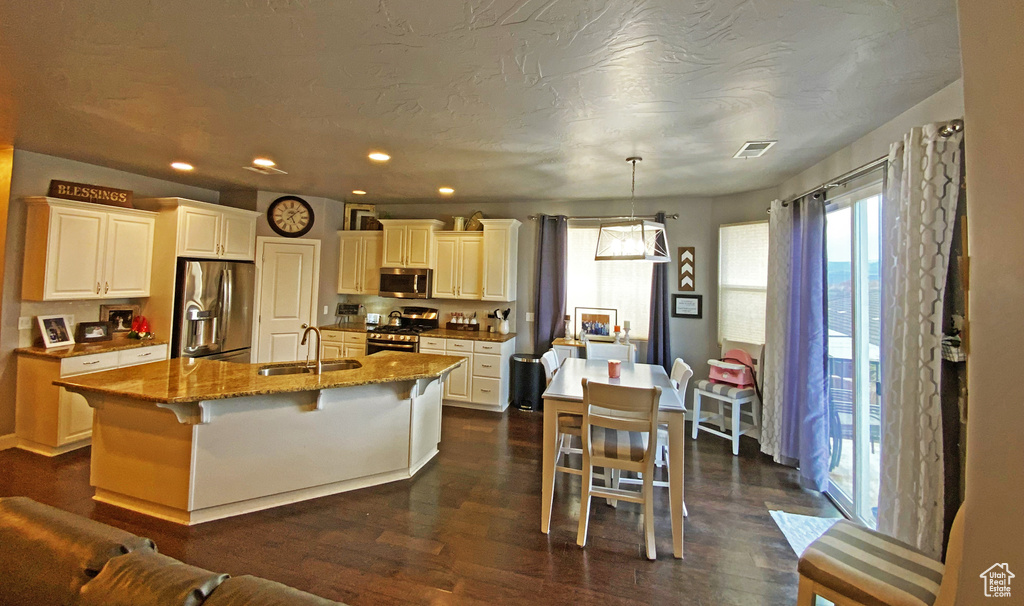 Kitchen with pendant lighting, an island with sink, stainless steel appliances, and a kitchen breakfast bar